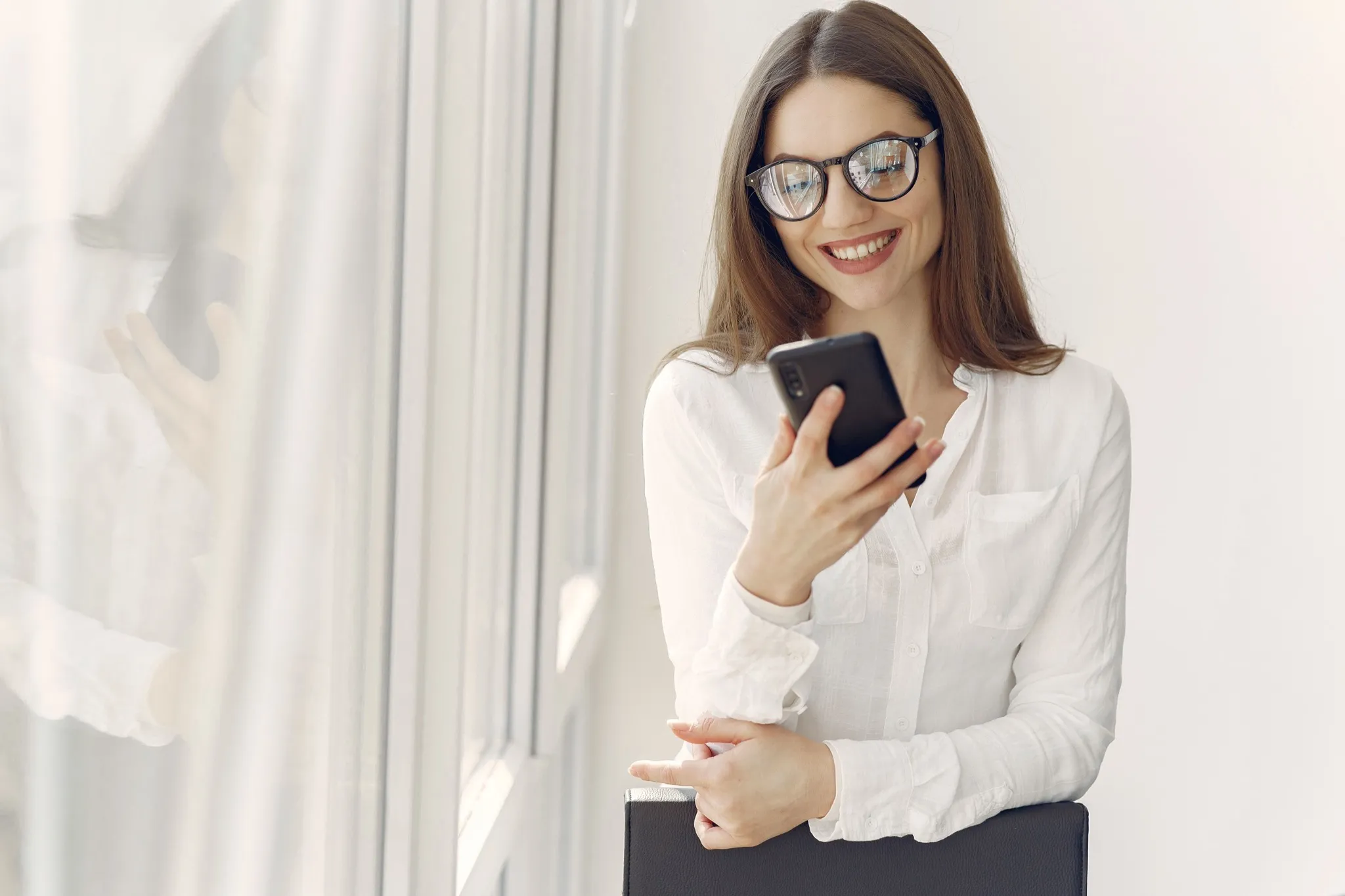 A professional reviewing information on a smartphone in a bright office setting